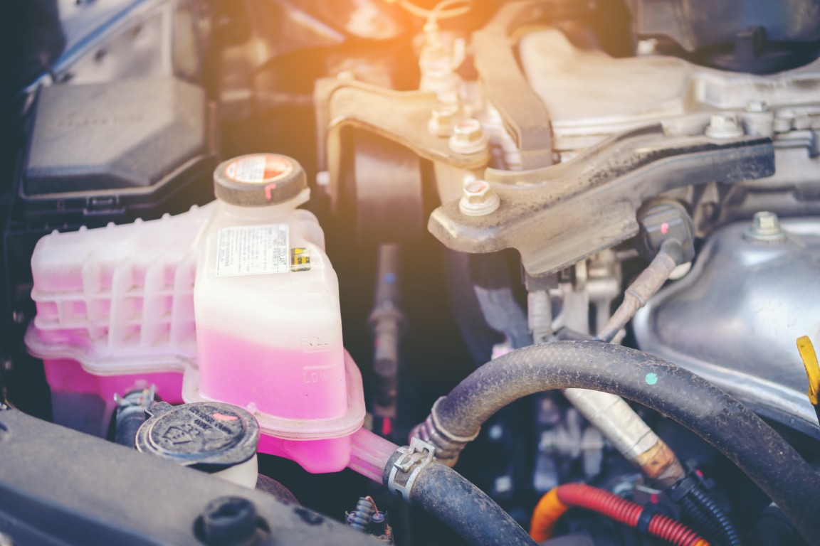 Coolant reservoir in an engine bay with the fluid level visible against the markings on the tank.