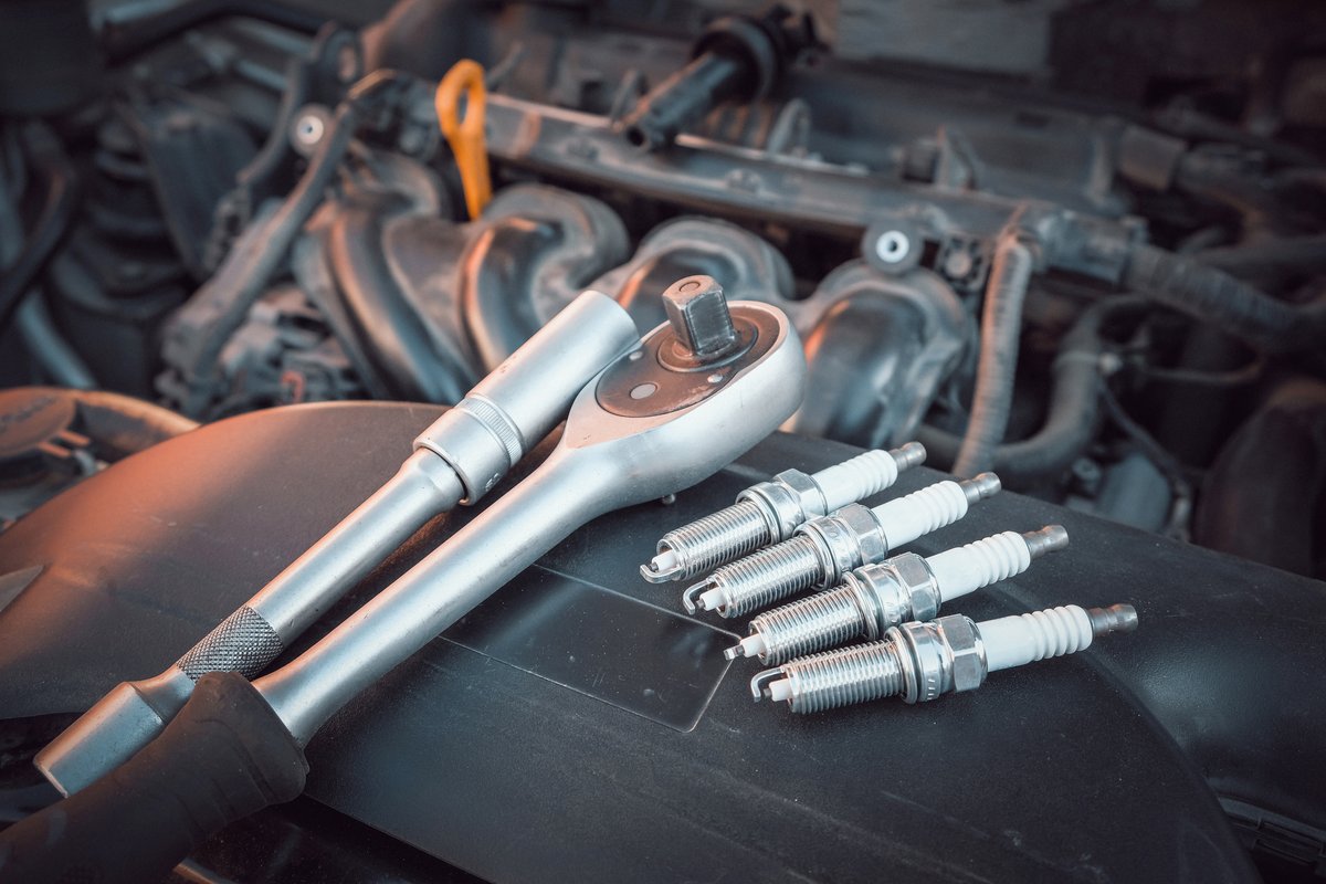 Set of spark plugs laid out with a ratchet during an ignition system service