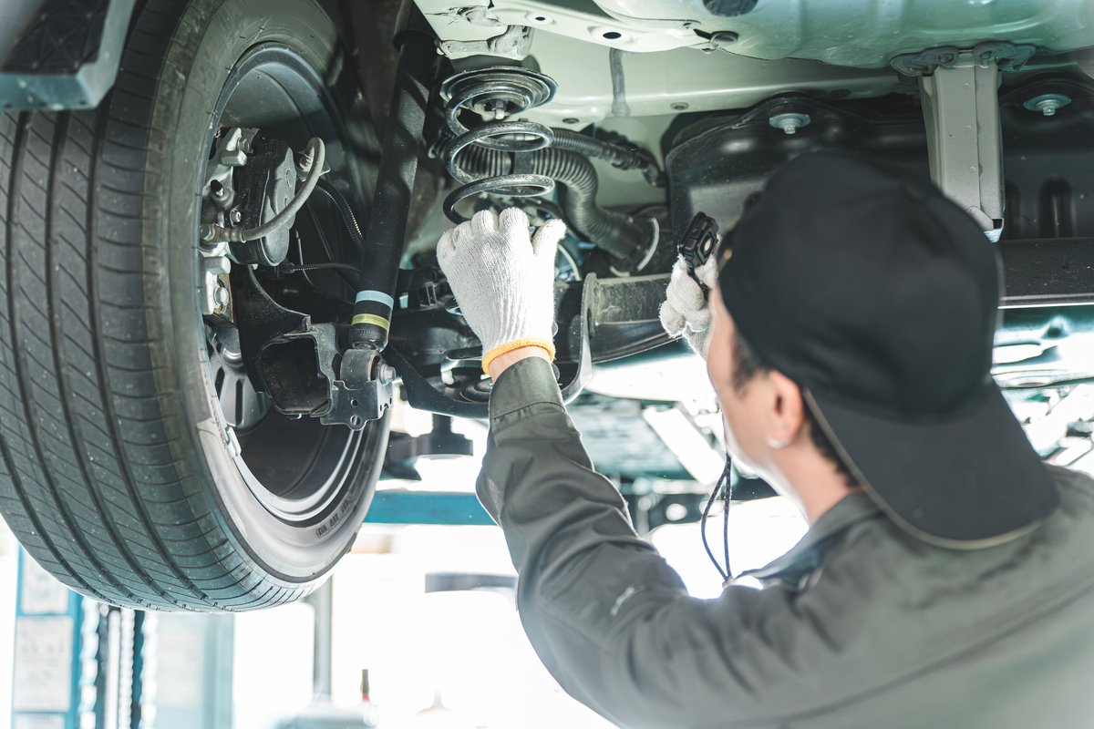 Technician inspecting suspension components under a vehicle on a lift