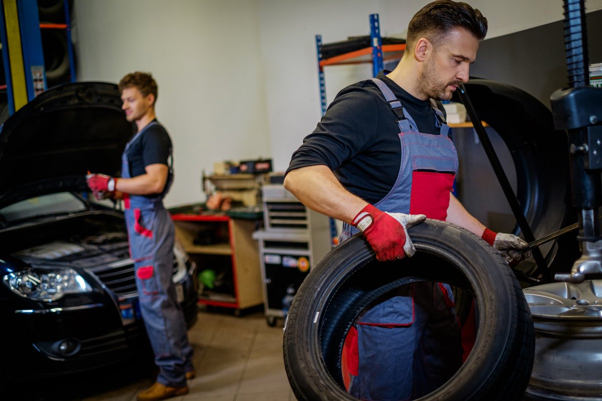 Technicians handling tires during a rotation service in an auto repair shop