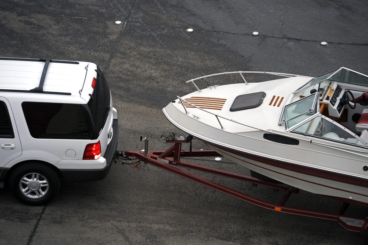SUV towing a boat on a trailer, ready for a summer trip to the lake