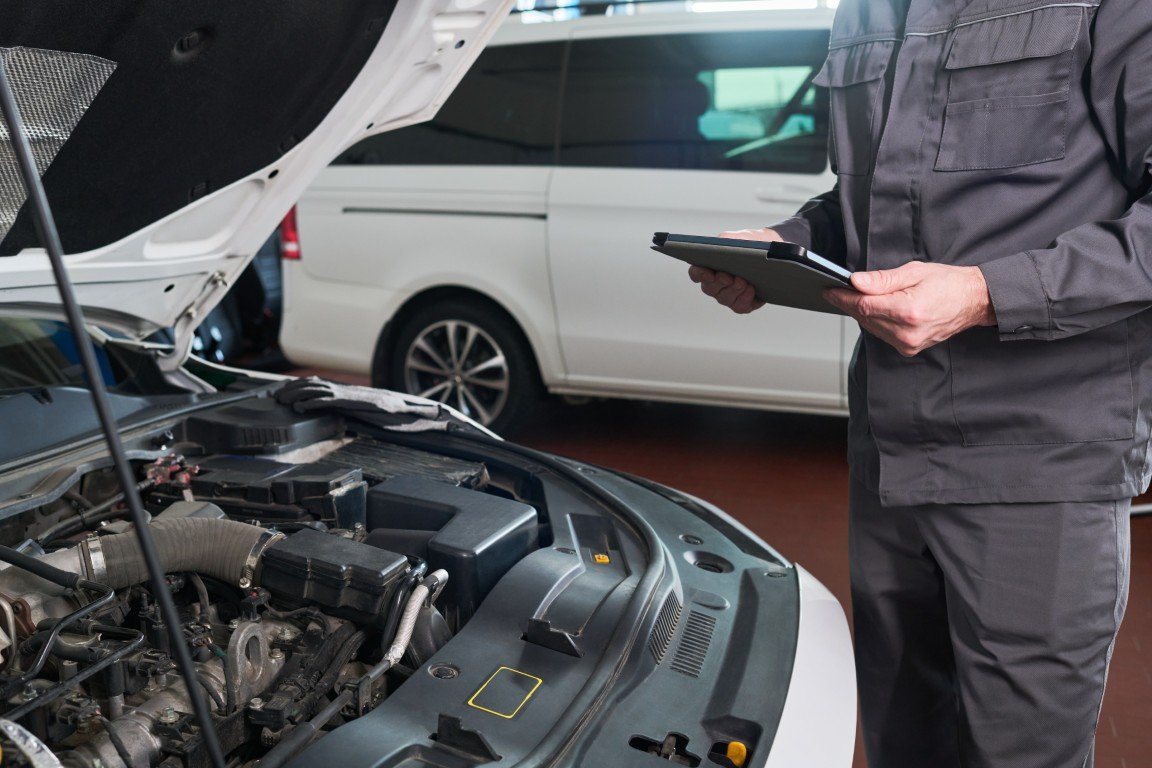Technician performing a thorough inspection on a used vehicle before purchase