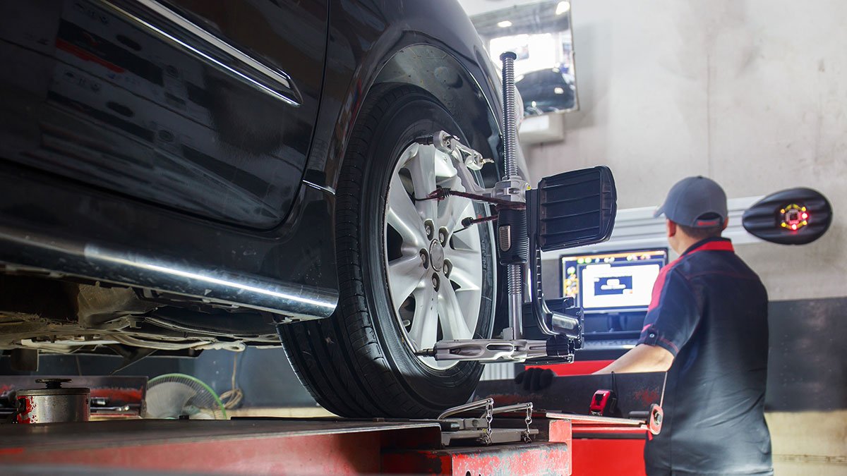 Vehicle on an alignment rack with measuring equipment attached to the wheel